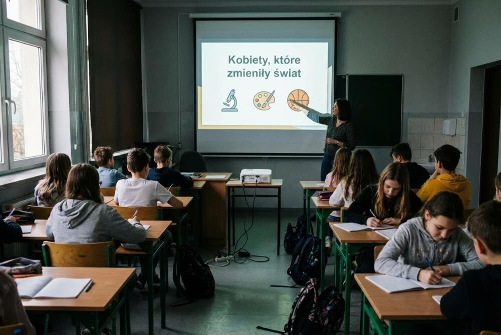Prezentacja w klasie o kobietach, które zmieniły świat, uczniowie słuchają i notują.