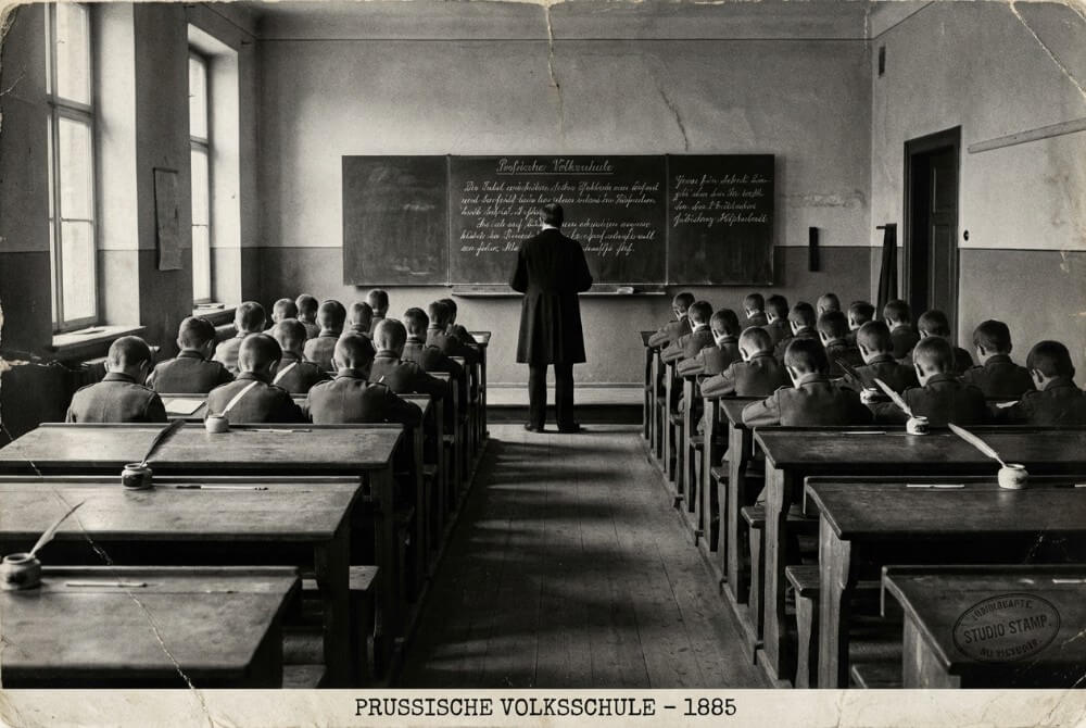 Surowa XIX‑wieczna sala szkolna w pruskim stylu, oddająca klimat dyscypliny i „zimnego chowu”.